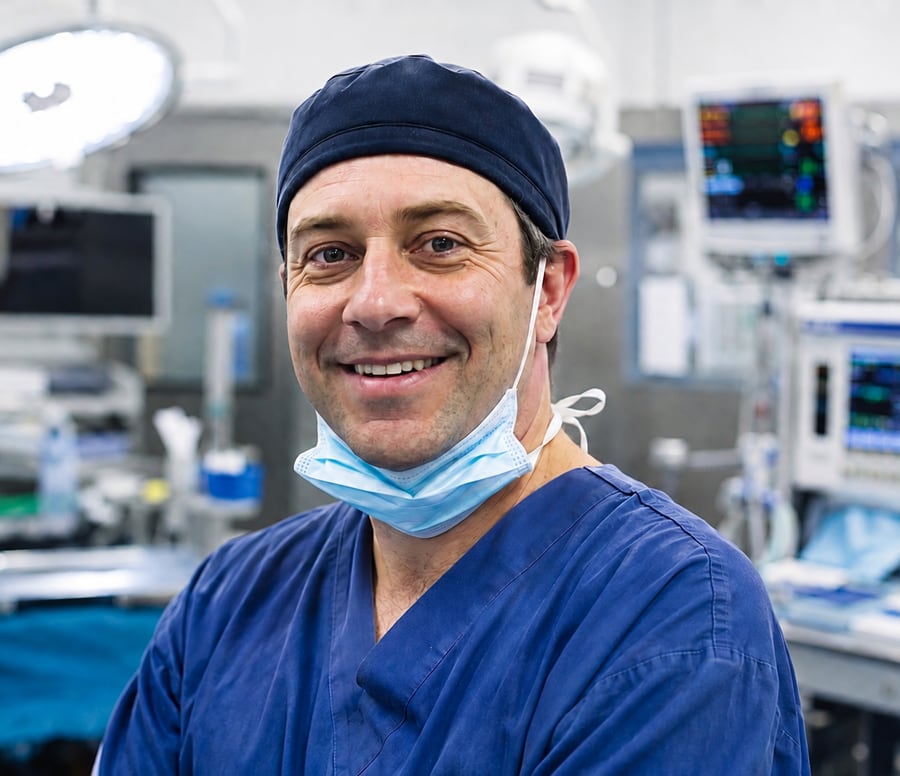 A surgeon in scrubs smiling in a hospital operating theatre